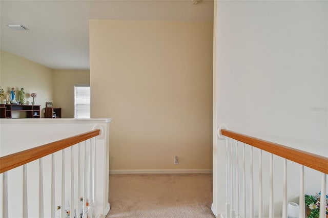 hallway with carpet, visible vents, baseboards, and an upstairs landing