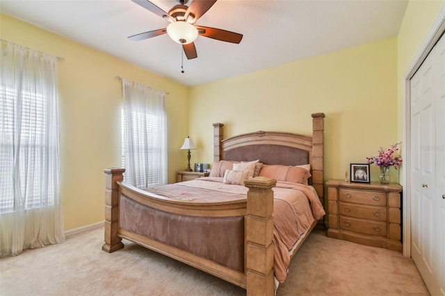 bedroom with ceiling fan, a closet, baseboards, and light colored carpet