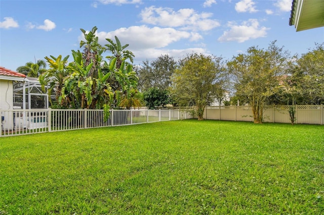 view of yard with a lanai and a fenced backyard