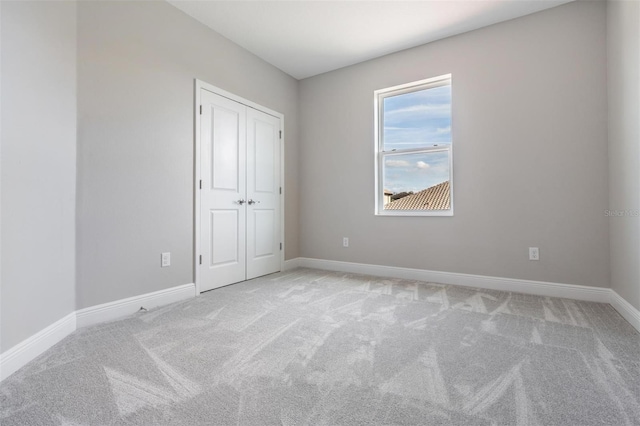 unfurnished bedroom with light colored carpet and a closet