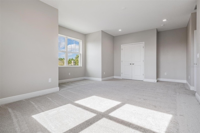 unfurnished bedroom with light carpet and a closet