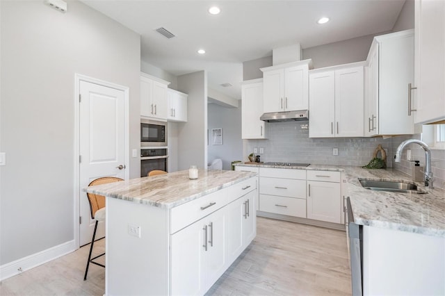 kitchen featuring white cabinetry, sink, a center island, light hardwood / wood-style floors, and black appliances