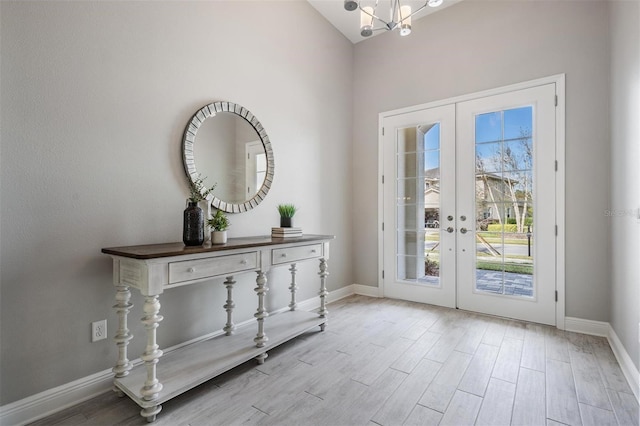 entryway with french doors, vaulted ceiling, an inviting chandelier, and light hardwood / wood-style flooring