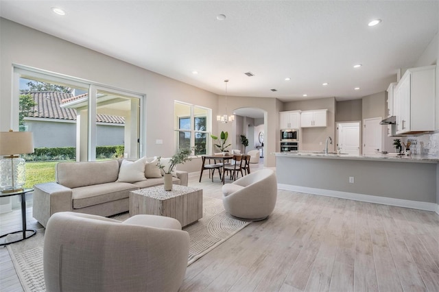 living room featuring light wood-type flooring, sink, and a chandelier