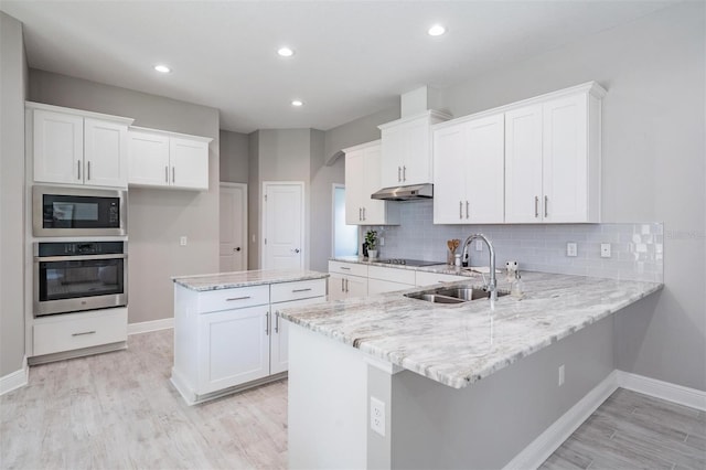 kitchen featuring light wood-type flooring, black microwave, sink, oven, and white cabinetry