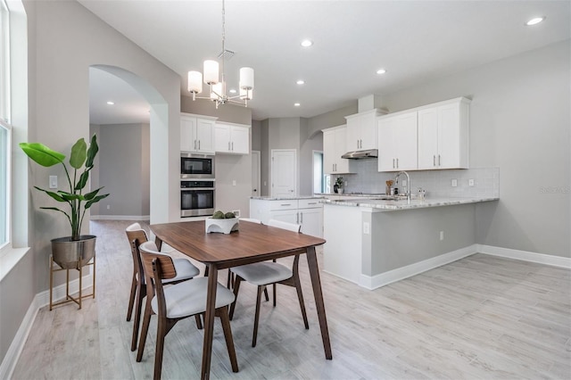 dining area with a notable chandelier, light hardwood / wood-style floors, and sink