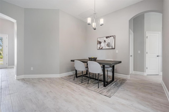 dining area with light wood-type flooring and an inviting chandelier