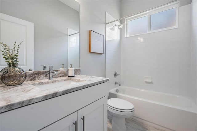 full bathroom with vanity, wood-type flooring, tiled shower / bath combo, and toilet