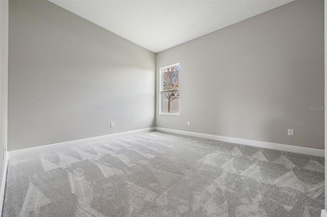 carpeted empty room featuring lofted ceiling