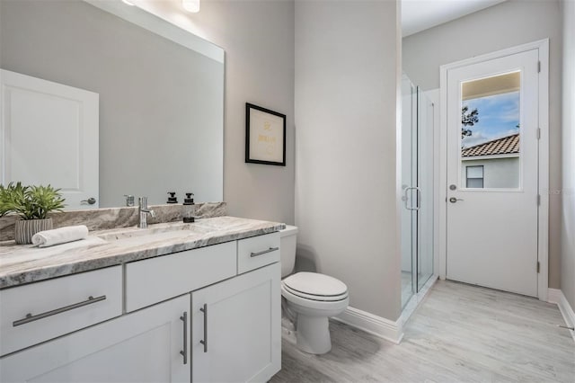 bathroom with hardwood / wood-style floors, vanity, toilet, and walk in shower