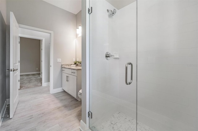 bathroom with toilet, hardwood / wood-style floors, vanity, and walk in shower