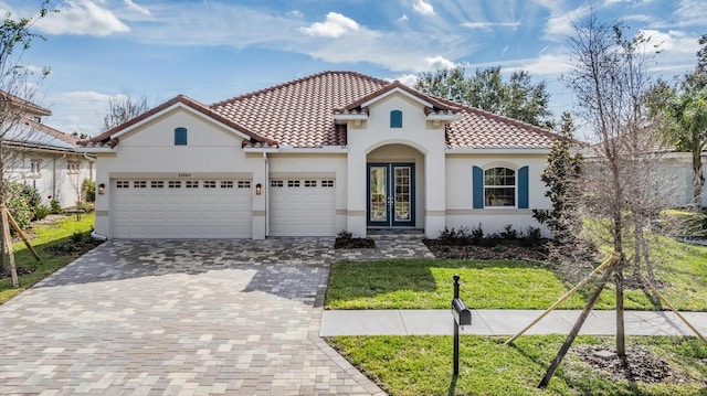 mediterranean / spanish home featuring a front lawn, a garage, and french doors