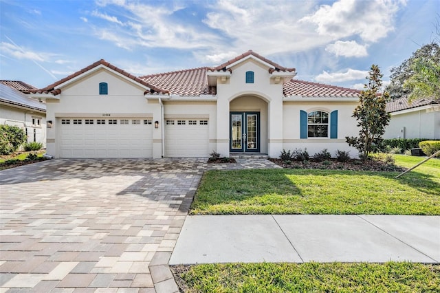 mediterranean / spanish house featuring french doors, a front yard, and a garage