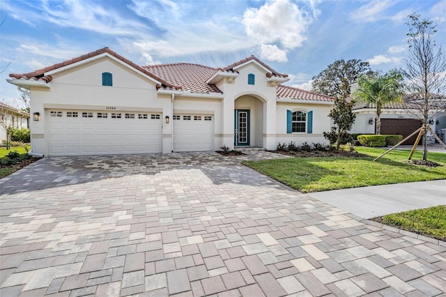 mediterranean / spanish-style house with a garage and a front lawn