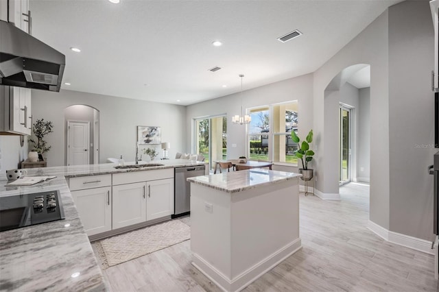 kitchen with white cabinets, light stone counters, dishwasher, and an island with sink