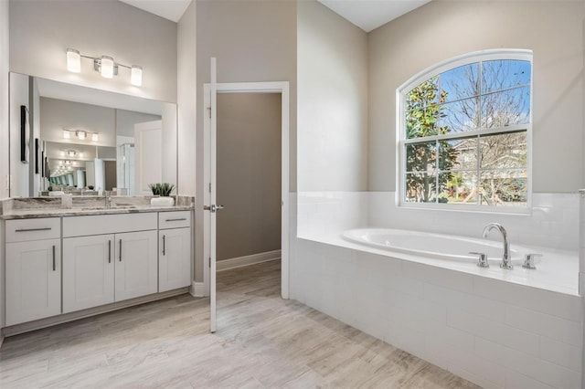 bathroom featuring tiled bath, vanity, and hardwood / wood-style flooring