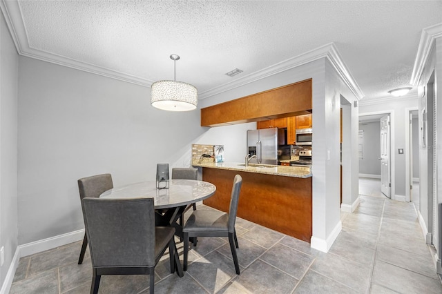 dining space with sink, tile patterned flooring, crown molding, and a textured ceiling