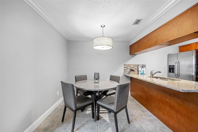 dining space with a textured ceiling, ornamental molding, and sink