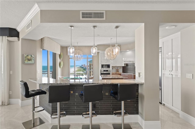 kitchen featuring a breakfast bar, appliances with stainless steel finishes, visible vents, and white cabinets