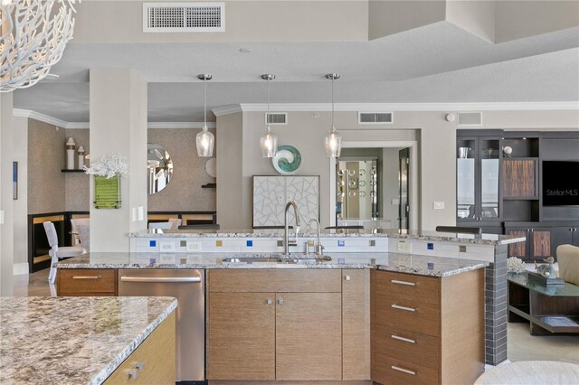 kitchen with crown molding, decorative light fixtures, light stone counters, sink, and stainless steel dishwasher