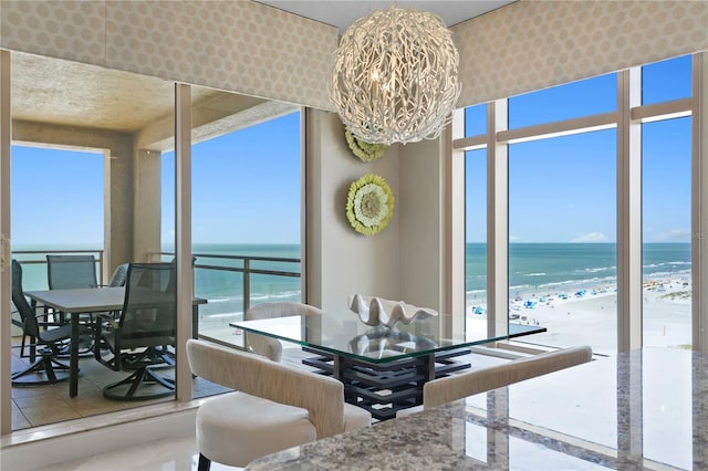 tiled dining area featuring a view of the beach, a water view, and a chandelier