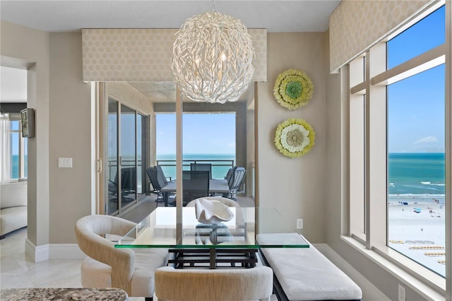 dining space featuring a water view, wallpapered walls, baseboards, and a chandelier