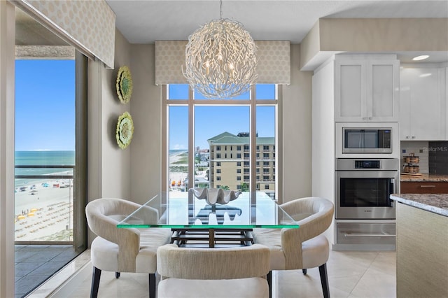 dining space with a water view, light tile patterned floors, and a notable chandelier