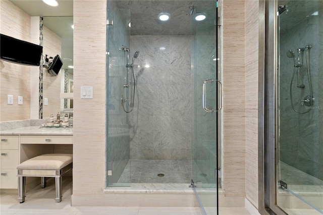 bathroom featuring a shower with shower door, vanity, and tile patterned floors