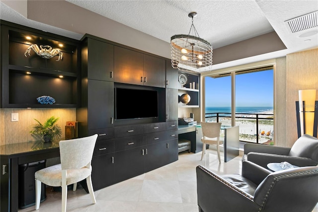 living area featuring a textured ceiling, built in shelves, visible vents, and an inviting chandelier