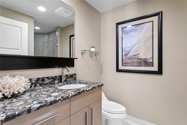 bathroom featuring tiled shower, vanity, and toilet