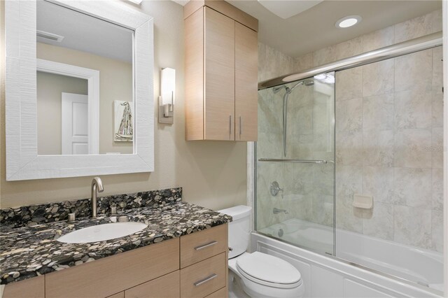 full bathroom featuring vanity, toilet, and bath / shower combo with glass door