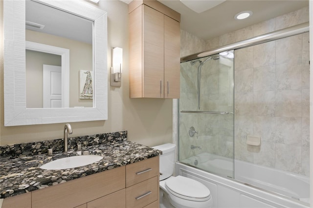 bathroom featuring toilet, visible vents, bath / shower combo with glass door, and vanity