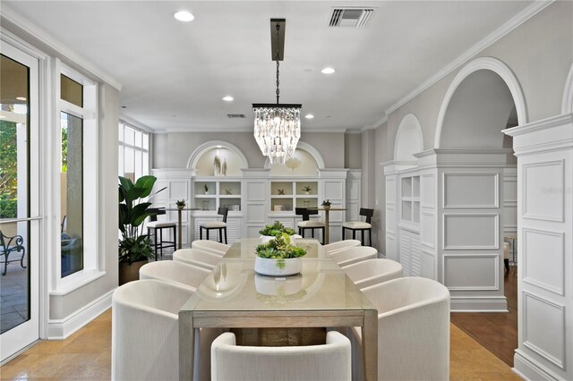 dining room featuring visible vents, a decorative wall, a notable chandelier, and ornamental molding