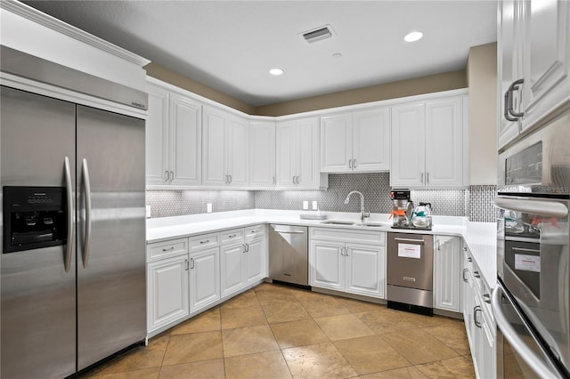 kitchen with light tile patterned floors, stainless steel appliances, sink, decorative backsplash, and white cabinets