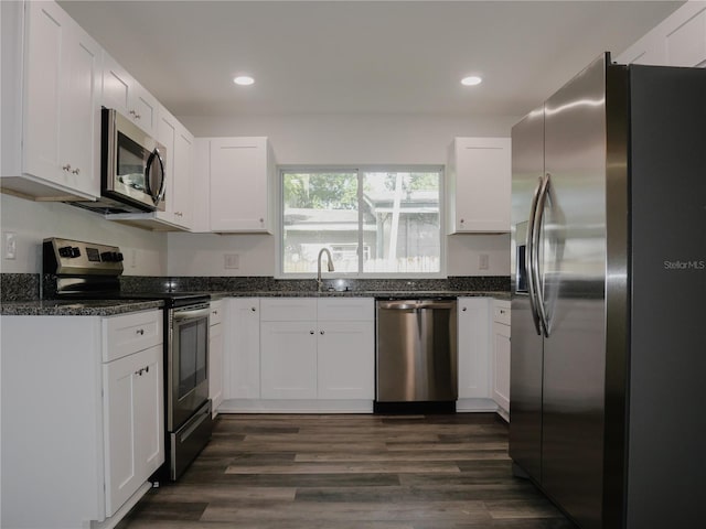 kitchen featuring a sink, dark stone countertops, appliances with stainless steel finishes, white cabinetry, and dark wood-style flooring