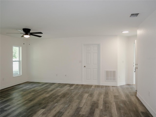 unfurnished room featuring visible vents, baseboards, and dark wood-style floors