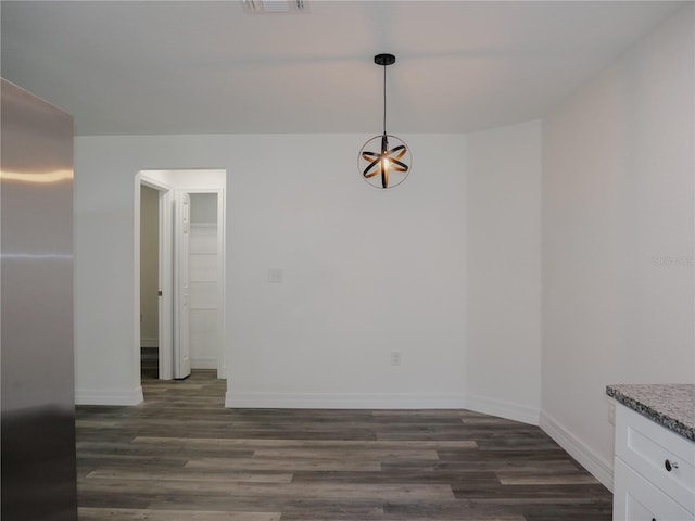 unfurnished dining area featuring dark wood finished floors and baseboards