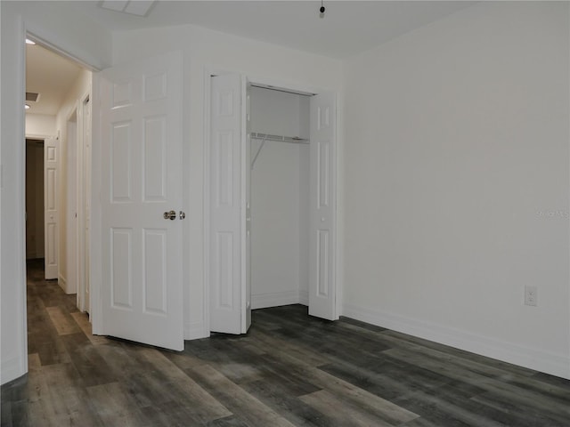 unfurnished bedroom with a closet, baseboards, and dark wood-type flooring