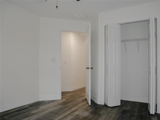 unfurnished bedroom with a closet, baseboards, and dark wood-style flooring