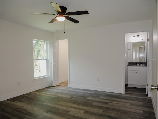 unfurnished bedroom with a sink, dark wood-style floors, connected bathroom, baseboards, and ceiling fan