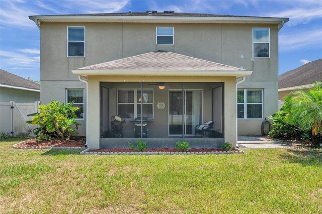 back of property with ceiling fan, a yard, and a sunroom