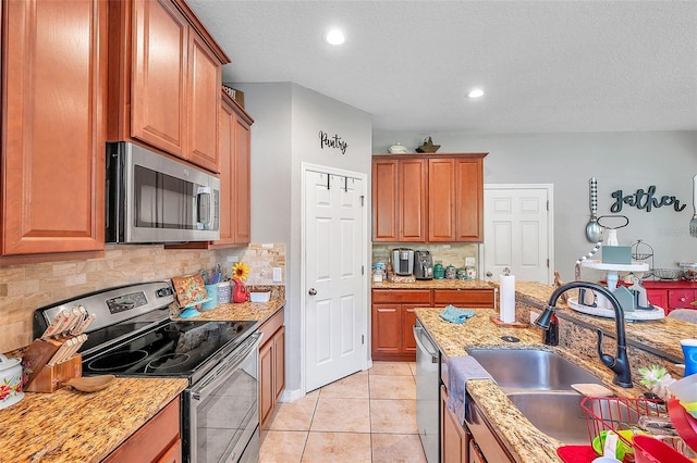 kitchen featuring stainless steel appliances, sink, light stone counters, light tile patterned floors, and decorative backsplash