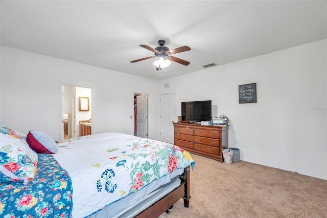 carpeted bedroom with ensuite bath and ceiling fan