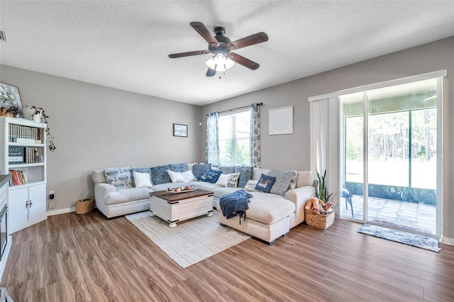 living room with ceiling fan, a textured ceiling, and hardwood / wood-style flooring