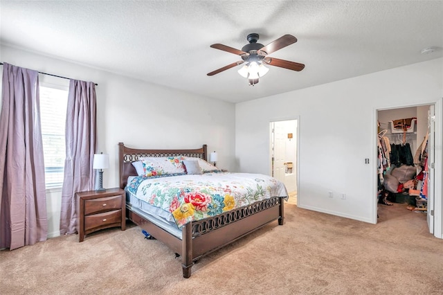 carpeted bedroom with a closet, ceiling fan, a spacious closet, a textured ceiling, and ensuite bathroom