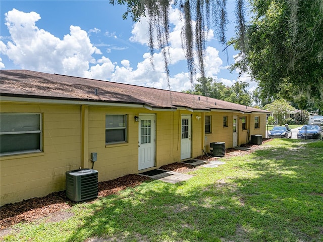 rear view of property with a lawn and central air condition unit