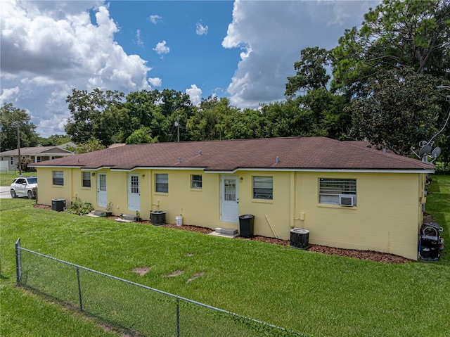 rear view of property with cooling unit and a lawn