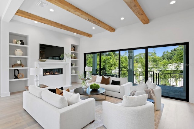 living room featuring beam ceiling, built in features, and light hardwood / wood-style floors