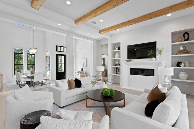 living room featuring beam ceiling, built in shelves, and light hardwood / wood-style floors