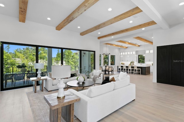 living room featuring light wood-type flooring, beam ceiling, and a wealth of natural light